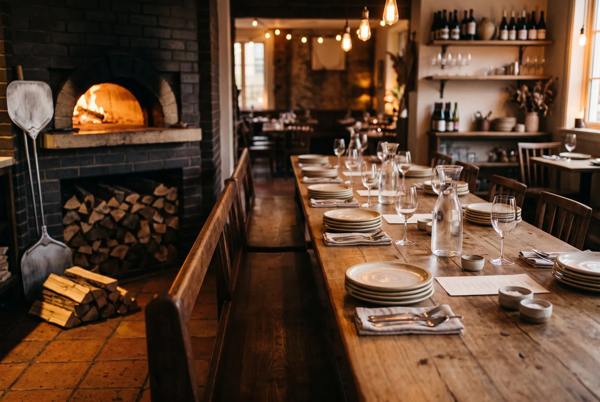 The long communal table beside the wood-fired oven