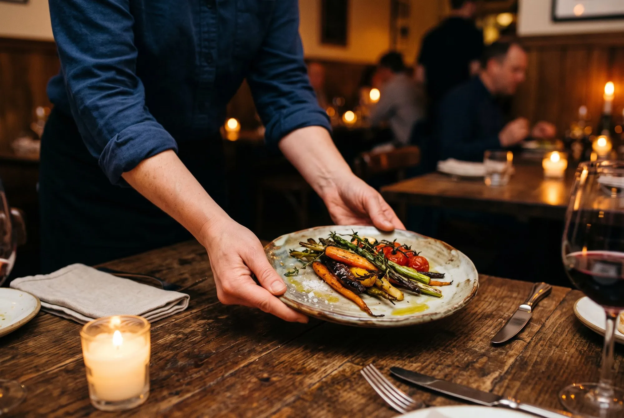 A plate of seasonal vegetables being set on the table